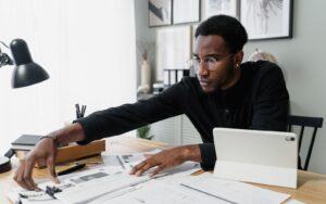 Profissional analisando relatórios financeiros impressos sobre a mesa com tablet ao lado, representando a comparação entre regimes tributários